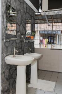 a bathroom with two sinks and a stone wall at Escape Backpackers KK in Kota Kinabalu