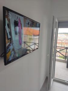 TV de pantalla plana colgada en una pared junto a una ventana en Eleven And A Half apartment en Nea Fokea