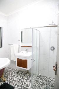 a white bathroom with a sink and a shower at modern, two-story luxury house in Gaborone