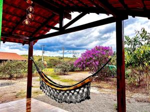 a hammock hanging from a pavilion with purple flowers at Chalé Verde morro da baleia. in Alto Paraíso de Goiás