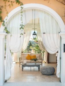ein Wohnzimmer mit weißen Vorhängen und einem Sofa in der Unterkunft La Vigne de Ramatuelle in Ramatuelle
