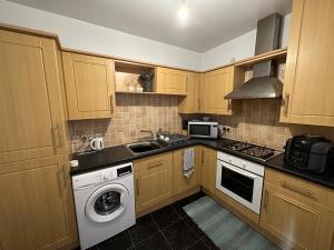 una cocina con armarios de madera, lavadora y fregadero en Shepherds View, Flat 8 en Derby