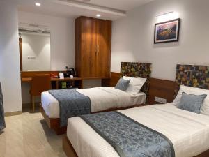 a hotel room with two beds and a desk at The Urban Hive Hotel in Belgaum