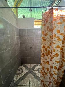 a shower with a shower curtain in a bathroom at La Muñequita Lodge 1 - culture & nature experience in Palmar Norte