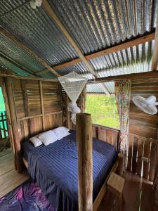 a bedroom with a bed in a wooden house at La Muñequita Lodge 1 - culture & nature experience in Palmar Norte