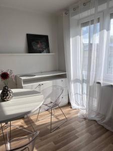 Cette chambre blanche dispose d'une table, de chaises et d'une fenêtre. dans l'établissement Apartment In The Old Town - Stare Miasto , Wi-Fi - by HIK Apartments, à Varsovie
