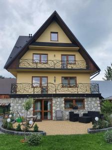 a large yellow house with a balcony on top at LONDYNEK in Poronin