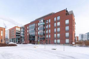 a large red brick building in the snow at MM City Apartment Ratina Close to Arena in Tampere