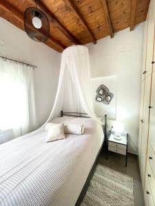 - une chambre avec un lit blanc et une moustiquaire dans l'établissement Lemon houses - Faros, Sifnos, à Faros