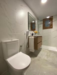 Baño blanco con aseo y lavamanos en Suites Benalup Centro, en Benalup-Casas Viejas