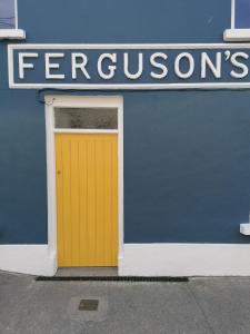 una puerta amarilla al lado de una tienda en Ferguson's Traditional Townhouse, en Dunkineely