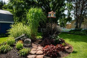 un jardín con un taburete, un banco y flores en The Georgetown Inn en Georgetown