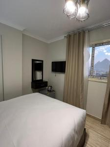 a bedroom with a large white bed and a television at Crowne Pyramids view inn in Cairo