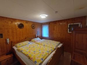 1 dormitorio con 1 cama en una pared de madera en Ferienhaus im Donauknie für Familien & Hunde, en Leányfalu