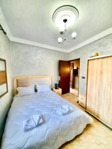 una camera da letto con un grande letto bianco e un lampadario a braccio di Amazing Home in Agafay area a Marrakech