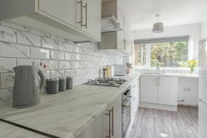 cocina con armarios blancos y encimera en Beautiful 3 bedroom House near West Bromwich -contractors, Family, NHS 