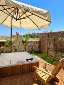 un patio con bañera de hidromasaje, sombrilla y silla en LAGOM HOTEL, en Seferihisar