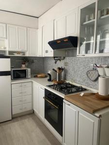 a kitchen with white cabinets and a black stove top oven at Appartamento a due passi dal centro in Pavia
