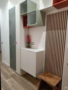 a small kitchen with white cabinets and a wooden bench at Lucania25 in Milan