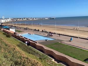 a swimming pool next to a beach with a pier at Isla's Haven Holiday Chalet in Bridlington