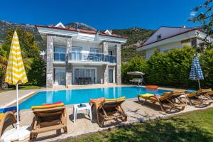 a swimming pool with chairs and a house at Yaşam Park Rena Villaları Ölüdeniz in Fethiye