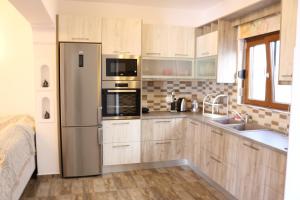 uma cozinha com armários de madeira e um frigorífico de aço inoxidável em Evilio em Alonissos