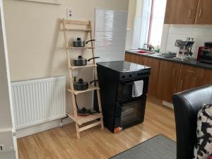 a kitchen with a stove and a shelf with pots on it at Corner House 51 Go Go Street Ground Floor Largs KA308JW 2 Bedroom in Largs