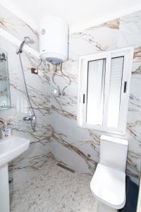 een badkamer met toilet, wastafel en raam bij ERLA'S apartment in Tirana