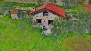 una antigua casa de piedra con techo rojo en una colina en The Mira House, en Ayvalık