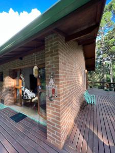 a brick house with a wooden deck at Chalés Vila Flor in Gonçalves