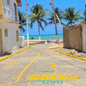 Japaratinga Suites في جاباراتينغا: شارع امام شاطئ فيه نخيل