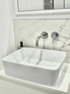 a white sink with a faucet in a bathroom at LUMI Apartament Mokotów in Warsaw