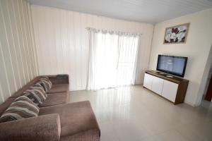 een woonkamer met een bank en een flatscreen-tv bij Casa Marfim - Piscina - Mariscal in Canto Grande