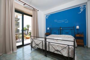 1 dormitorio con 1 cama con pared azul en Hotel Donna Rosa en SantʼAlessio Siculo