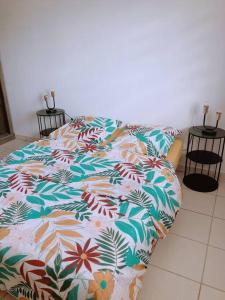 uma cama num quarto com um cobertor florido em Appartement T3 chic et cosy em Caiena