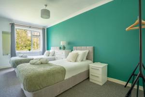 a bedroom with two beds and a blue wall at Raymond James Accommodation, sleeps up to 7, free parking, full amenities and garden in Peterborough