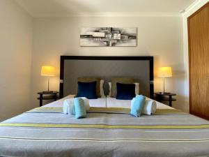 una camera da letto con un letto grande con cuscini blu di Flor da Primavera by CORAL a Mexilhoeira Grande