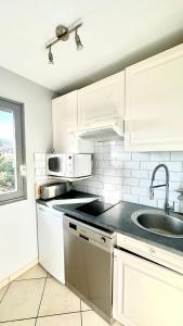 a white kitchen with a sink and a microwave at DEAUVILLE LES YEARLING Appartement duplex 2 chambres 4 pers Balcon Plein Sud in Deauville