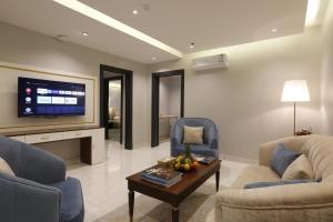 sala de estar con 2 sillas, mesa y TV en وايت مون للاجنحة الفندقية الضيافة, en Khamis Mushayt