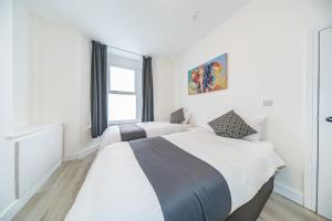 2 łóżka w białej sypialni z oknem w obiekcie Hosted By Ryan - Huge 5 Bedroom House w Liverpoolu
