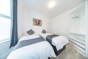 2 łóżka w pokoju z białymi ścianami i oknem w obiekcie Hosted By Ryan - Huge 5 Bedroom House w Liverpoolu