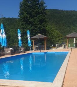 einen Pool mit blauen Sonnenschirmen und Stühlen in der Unterkunft Arena Villa Apartmani in Bihać