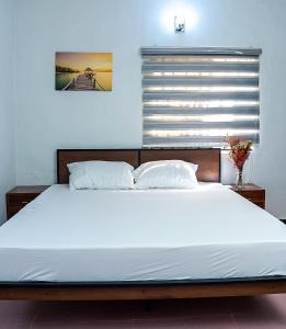um quarto com uma grande cama branca e uma janela em Palm Heights Apartments - Omole Phase 1, Ikeja em Ikeja