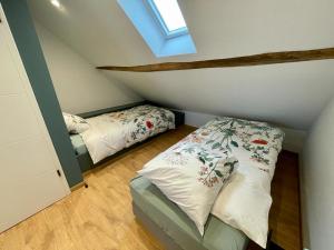 een slaapkamer op zolder met 2 bedden en een raam bij Gite de Clermont in Thimister