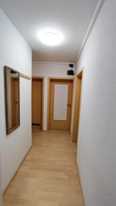 a hallway with white walls and a wooden floor at Zimmervermietung38 - Nebel in Salzgitter