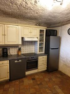 a kitchen with white cabinets and a stainless steel refrigerator at Gite troglodyte Les Iris in Villiers-sur-Loir
