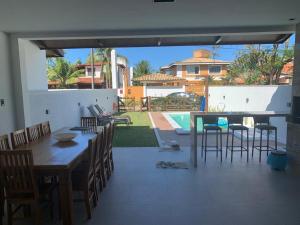 a patio with a table and chairs and a pool at Casa 4 suítes com piscina Condomínio Lagoa Dourada Ilha de Itaparica BA in Vera Cruz de Itaparica