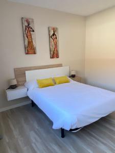 una camera da letto con un grande letto bianco con due immagini sul muro di Villa Inda a Gran Tarajal