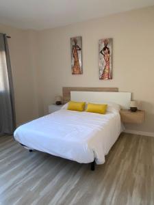 sypialnia z dużym białym łóżkiem z żółtymi poduszkami w obiekcie Villa Inda w mieście Gran Tarajal
