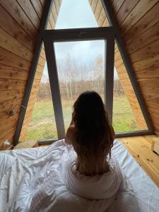 ビャウォヴィエジャにあるŚwironekの窓際のベッドに腰掛けている女性